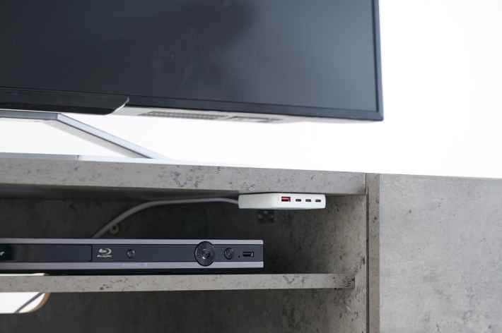 テレビボードに設置された白いNovaPort SLIM QUAD充電器
