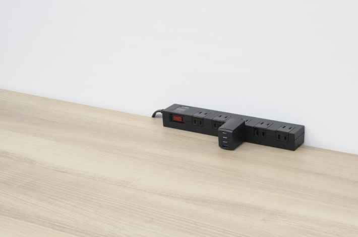デスクの隅に置かれた延長電源タップと充電器