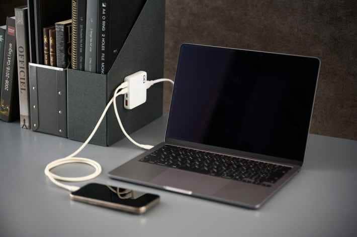 ファイルスタンドに設置され、ノートPCとスマートフォンを充電する白いNovaPort SLIM QUAD充電器