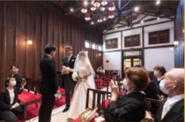 教会で結婚式を挙げているカップルと参列者の様子。
